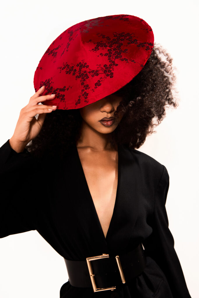 Model wearing a fascinator hat, covering her eyes for a fashion photoshoot.